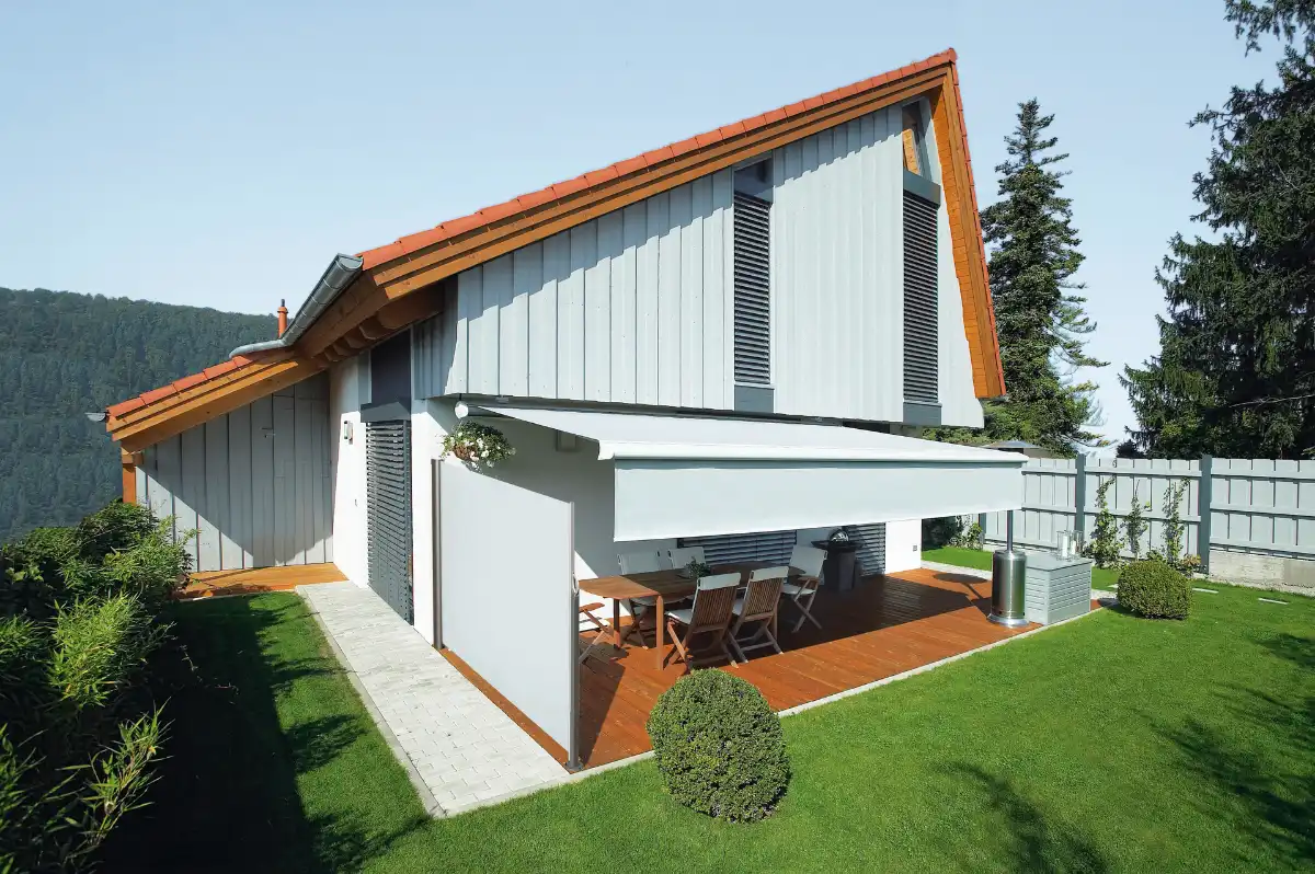 Modernes Einfamilienhaus mit mit weißer Markise und seitlichen Volant Rollos